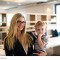 Blonde Frau im Büro mit kleinem Kind auf dem Arm