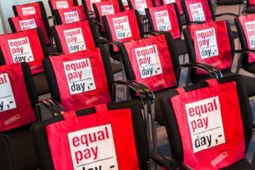 Stühle mit roten Equal Pay Day Taschen über der Rückenlehne